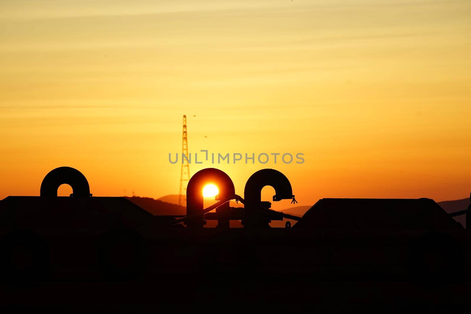 Beautiful sunset on industrial background. The sun shines through the curved pipes. The orange light and the black silhouettes.