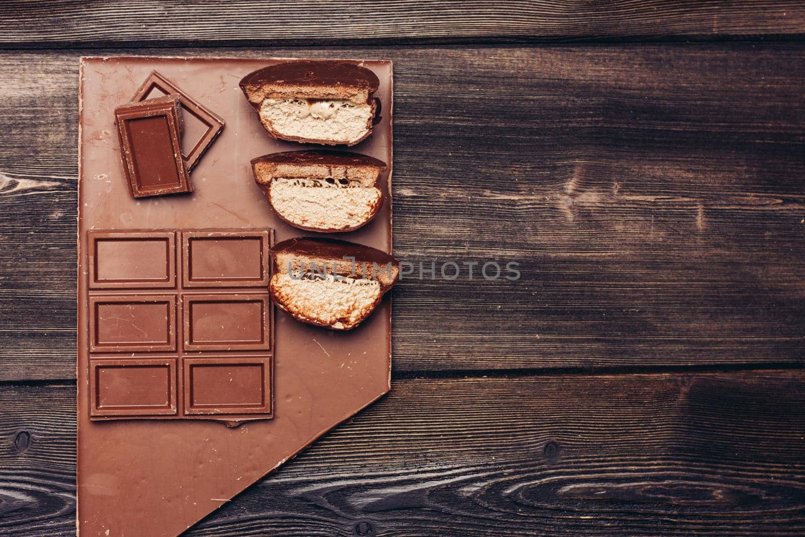 brownie with chocolate icing cut in half and candy cubes on wooden table. High quality photo