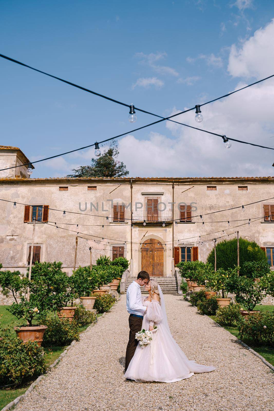 Florence, Italy - 01 october 2019: Wedding in Florence, Italy, in an old villa-winery. Wedding couple walks in the garden. Loving bride and groom. by Nadtochiy