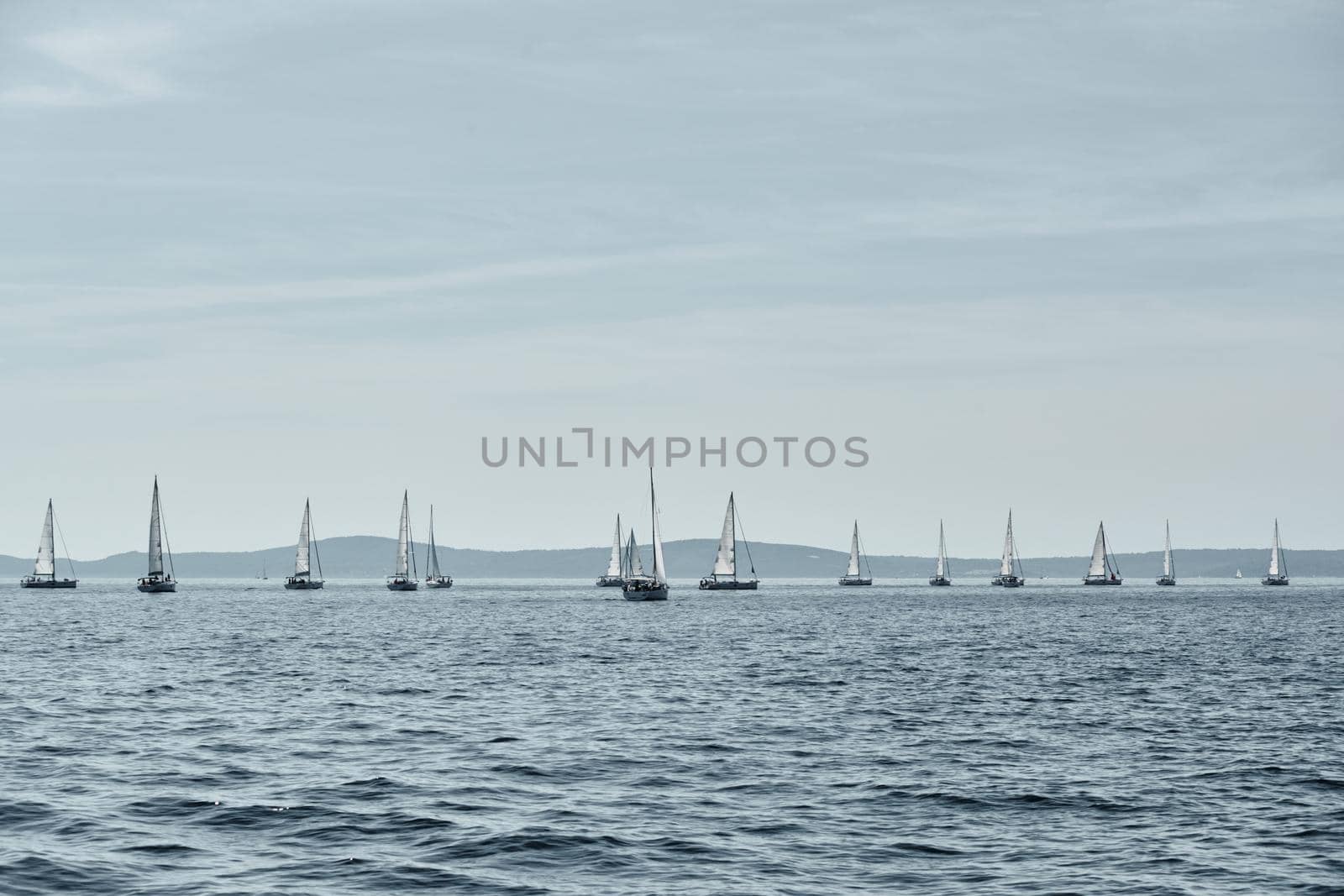 Beautiful sea landscape with sailboats, the race of sailboats on the horizon, a regatta, a Intense competition, island with windmills are on background