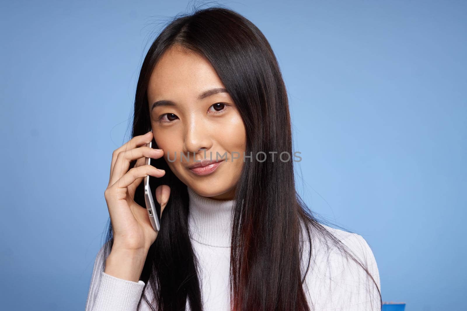 Asian woman limbs talking on the phone on blue background studio by SHOTPRIME