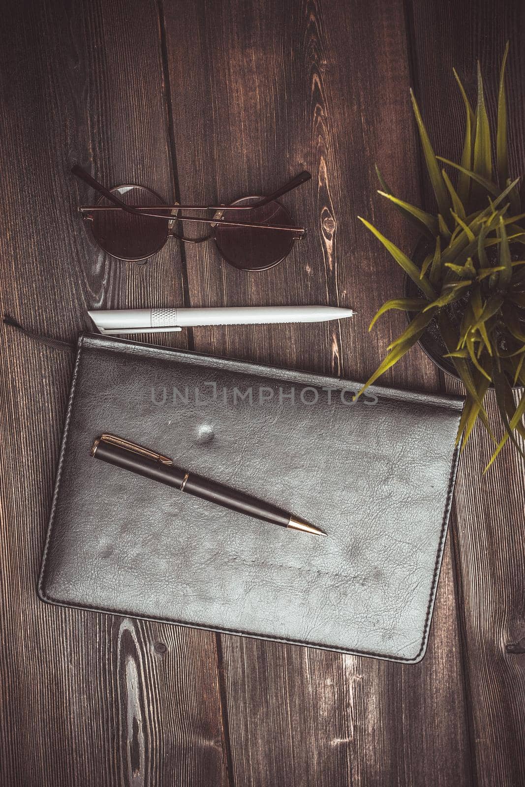 notepad glasses and a flower in a pot on a wooden table top view pen office. High quality photo