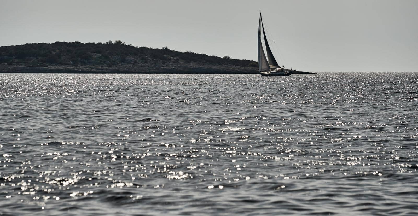 Beautiful sea landscape with lonely boat on the horizon, island is on background, colorful