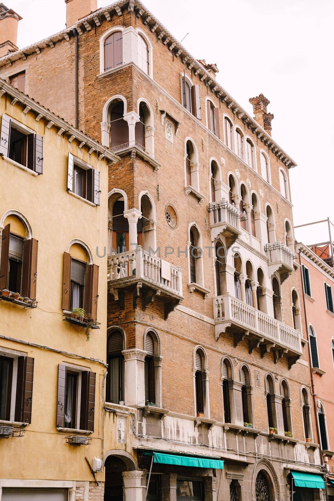 A five-storey stone building with white balconies with columns, classic Venetian arched windows.