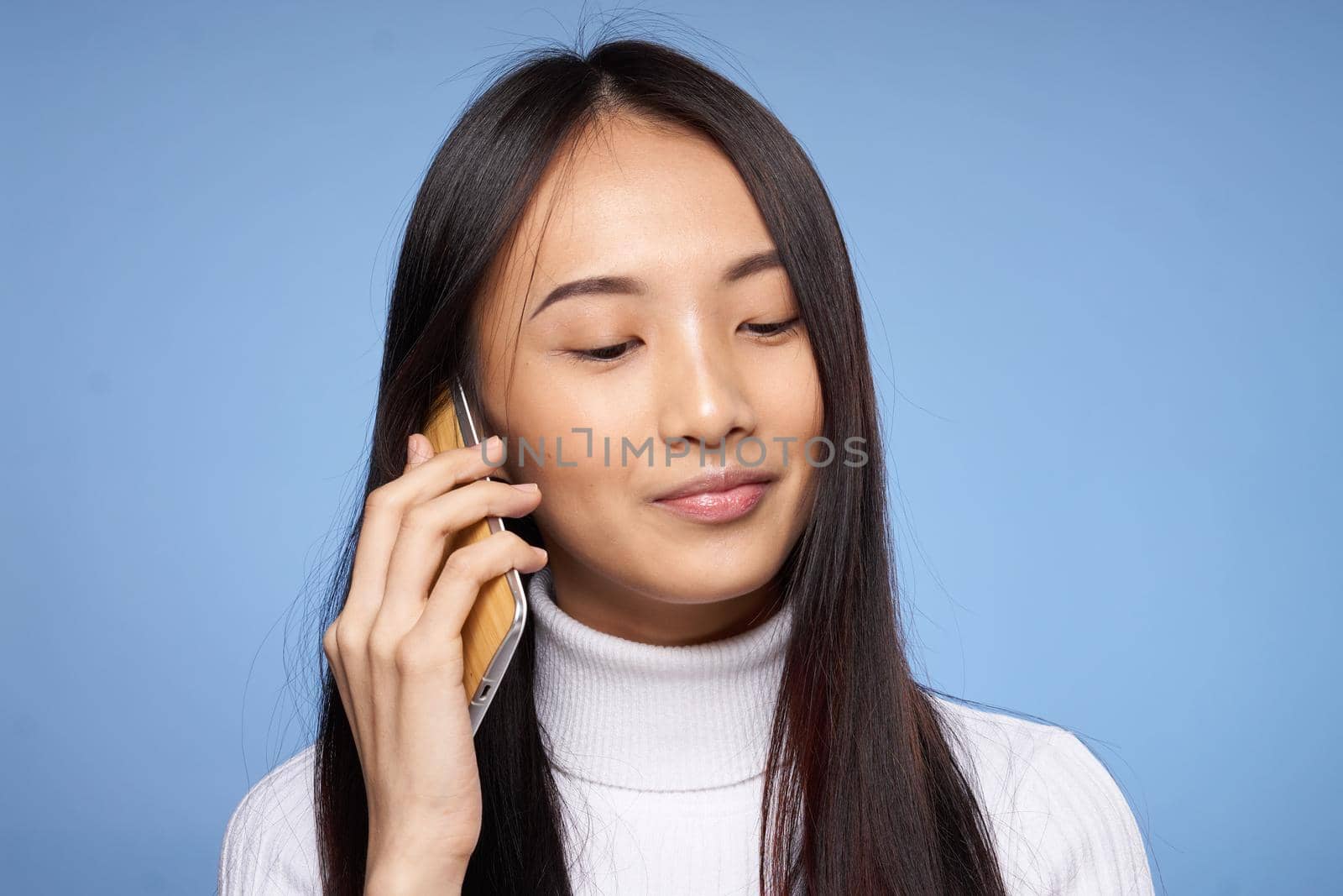 cute asian woman talking on the phone technology blue background. High quality photo