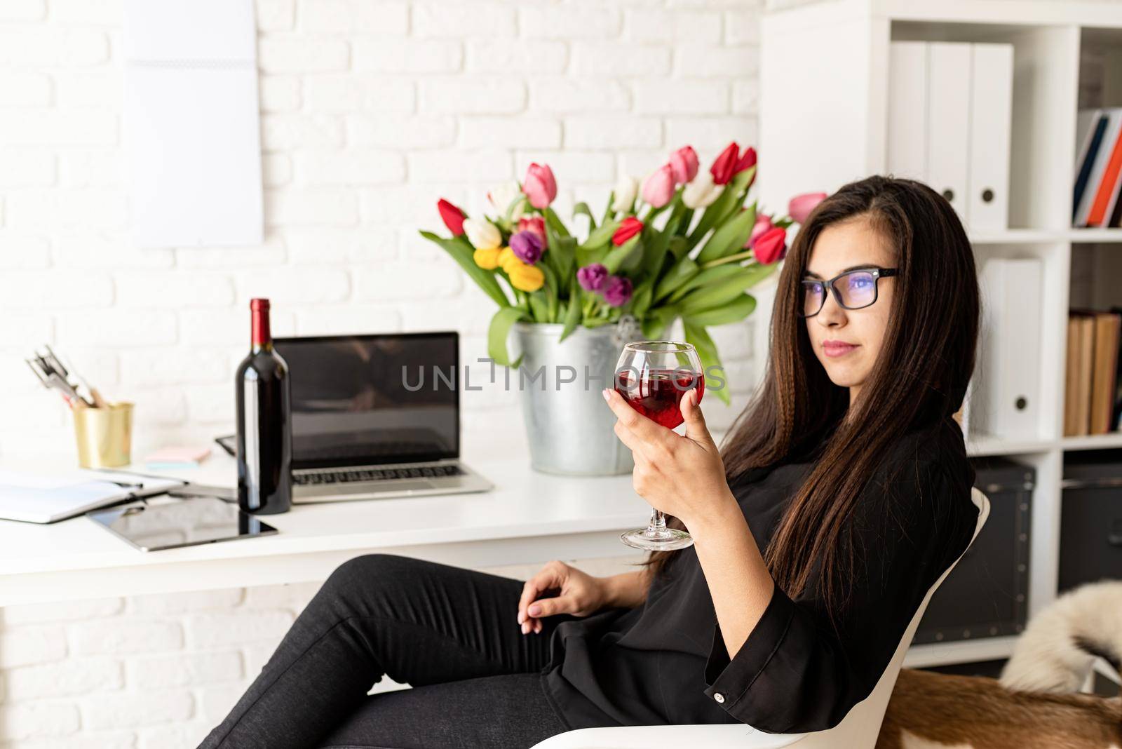 Small business concept. Young confident business woman drinking wine, celebrating at home office