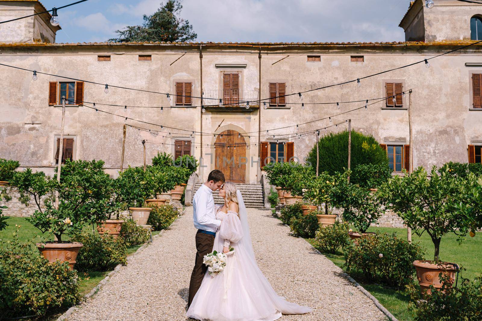 The wedding couple walks in the garden. Lovers of the bride and groom. Wedding in Florence, Italy, in an old villa-winery.