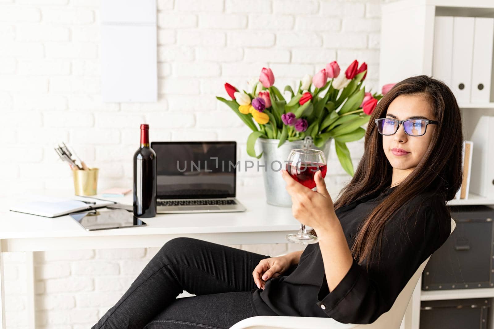Young confident business woman florist drinking wine, celebrating at the office by Desperada