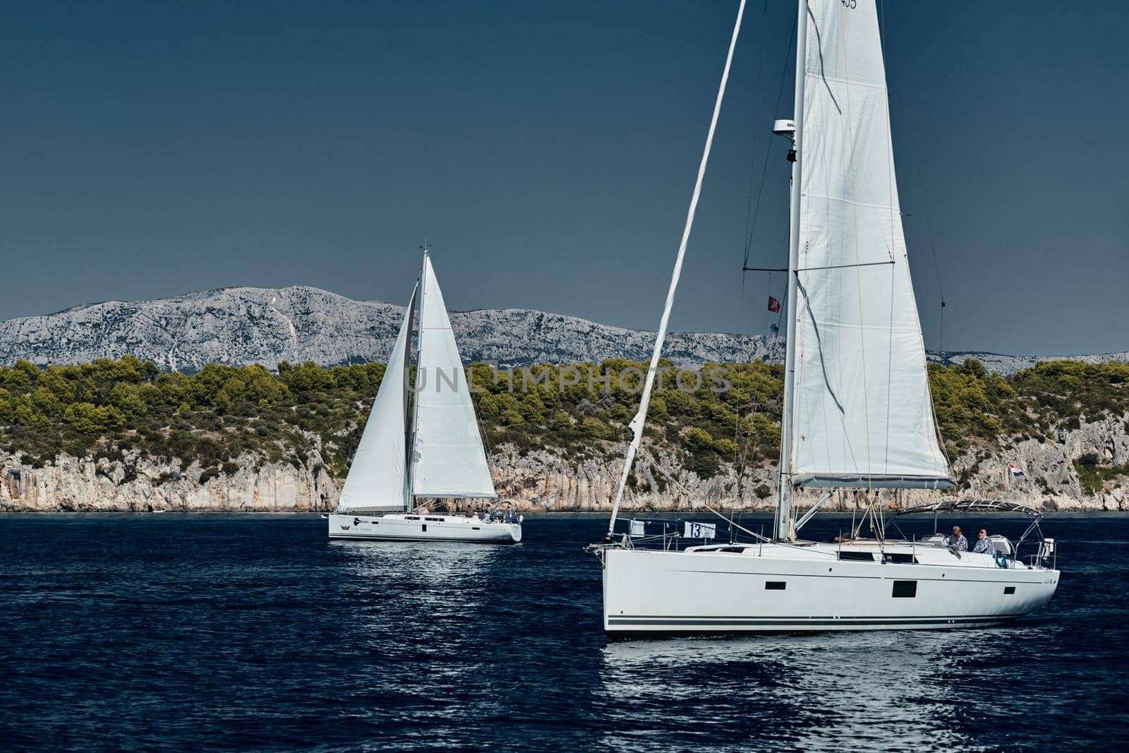 Croatia, Adriatic Sea, 15 September 2019: The race of sailboats, a regatta, reflection of sails on water, Intense competition, bright colors, island with windmills are on background by vladimirdrozdin