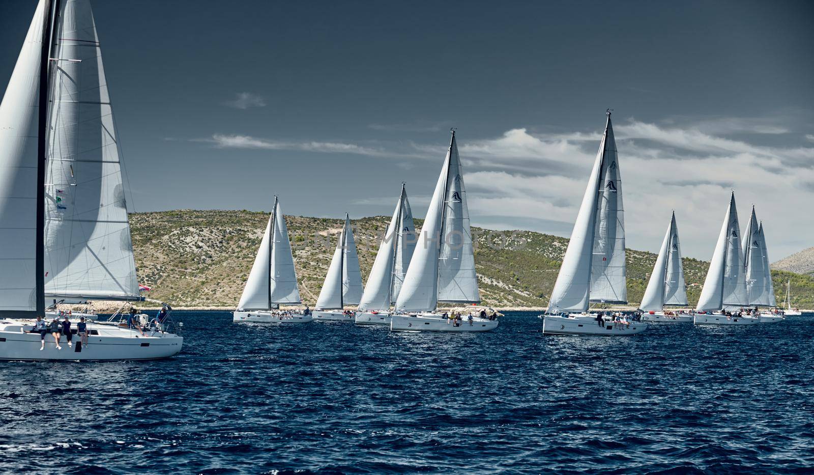 Croatia, Adriatic Sea, 18 September 2019: Sailboats compete in a sail regatta, sailboat race, reflection of sails on water, island is on background, clear weather