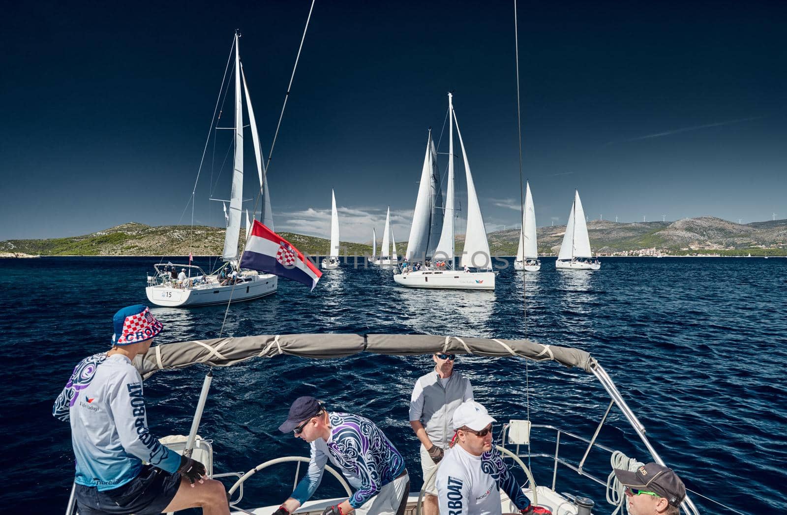 Sailboats compete in a sail regatta, the team turns off the boat, reflection of sails on water, multicolored spinnakers, number of boat is on aft boats, Croatia, Mediterranean Sea, 18 September 2019