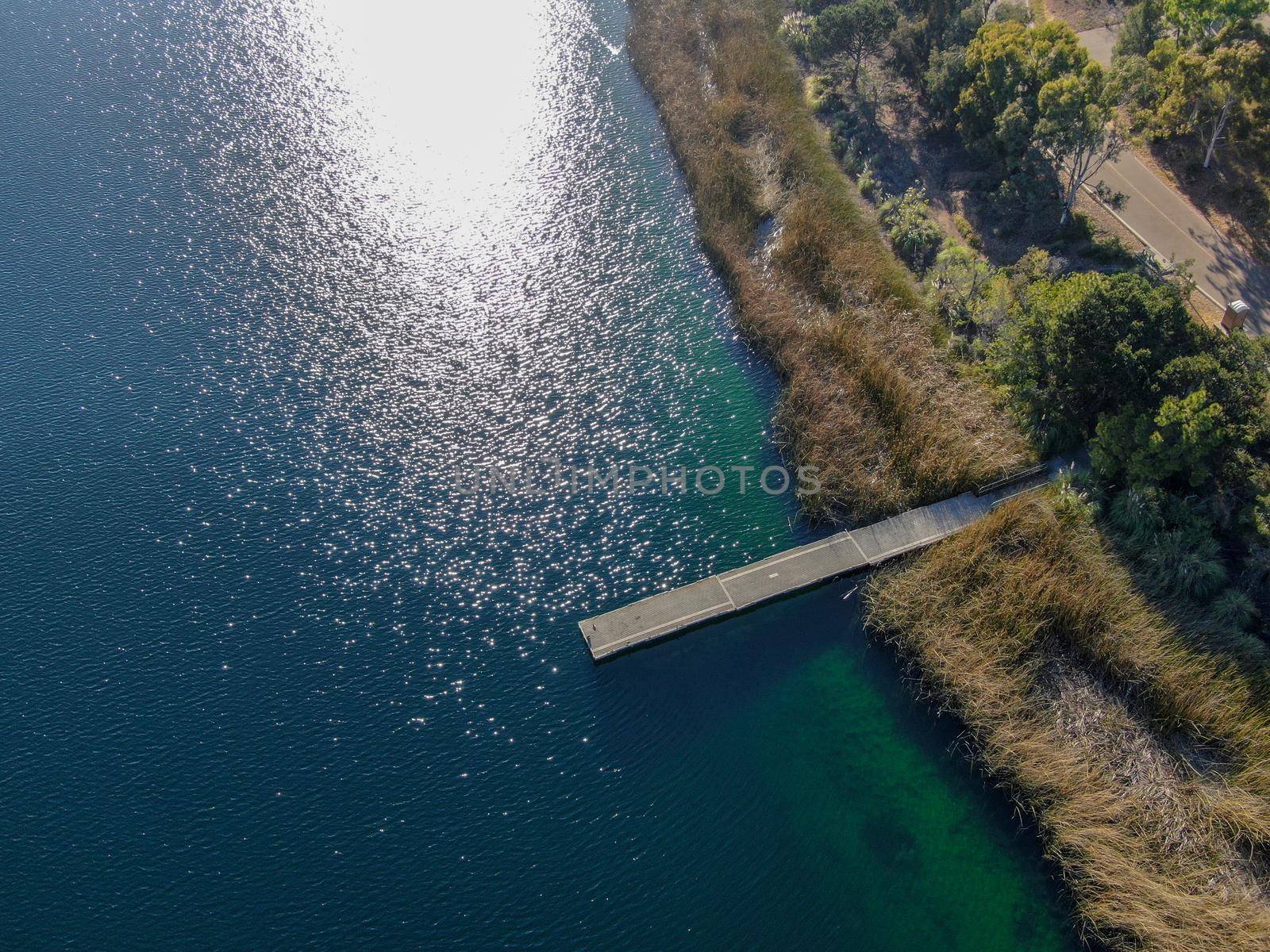 Aerial view of wood pier with fishers and their fishing rods trying to catch fish at the Miramar lake, San Diego, California. USA. Recreation site including boating, fishing, motor boat. 