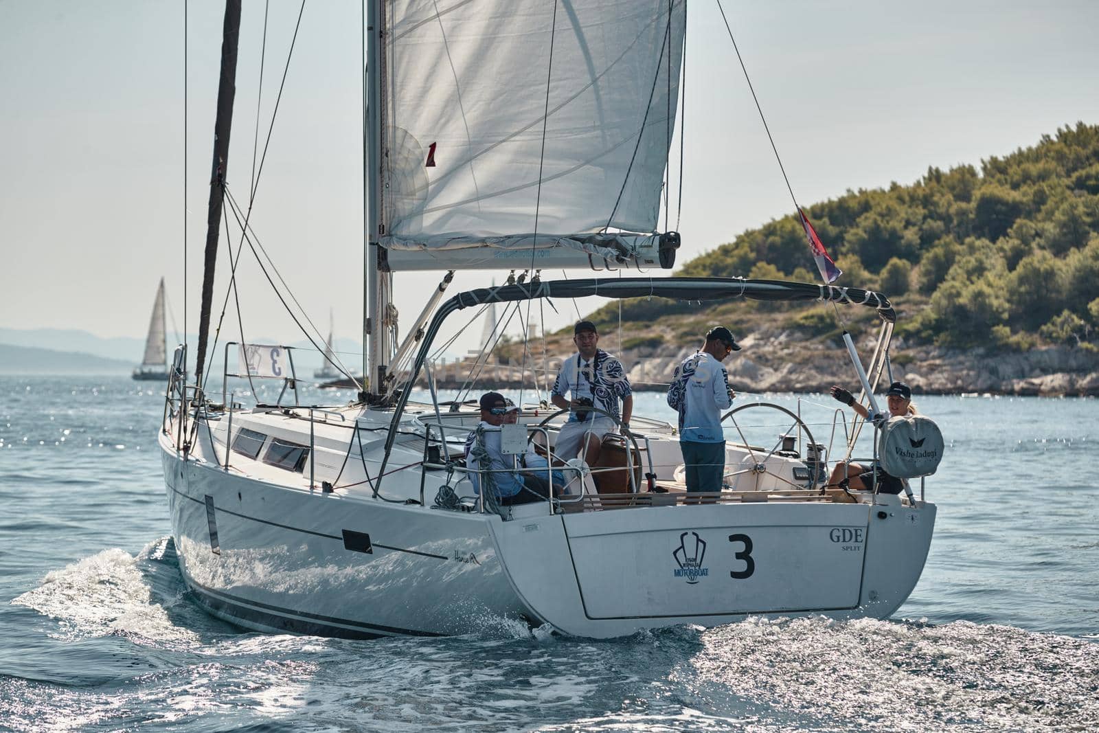 Croatia, Adriatic Sea, 15 September 2019: People have a good time on the sailboat, island with windmills are on background