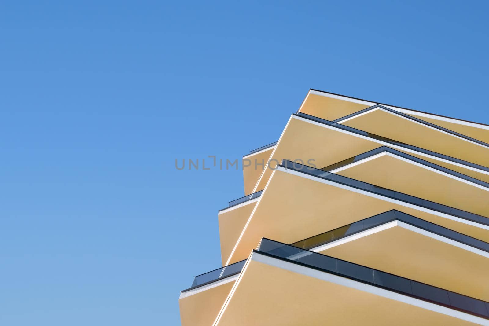 Modern architecture building facade with balconies. New apartments. Design elements contemporary building detail architecture concrete and glass facade on clear blue sky background real estate concept by synel