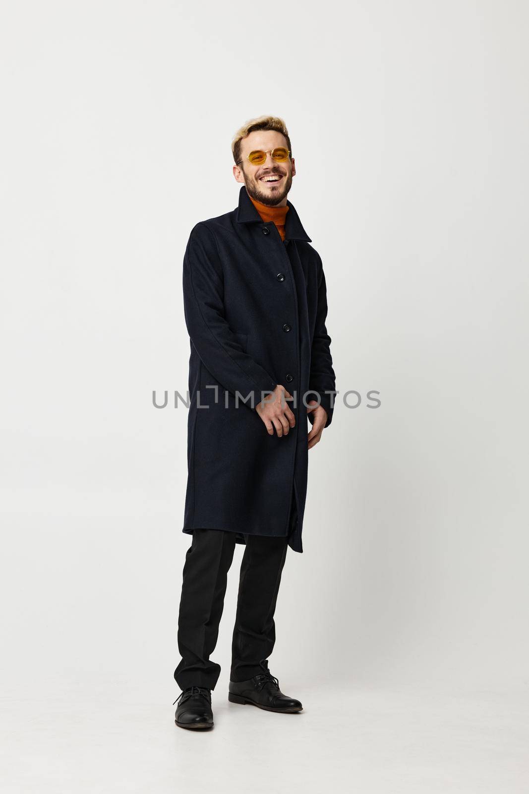 male model in a black coat and pants boots light background pose Copy Space by SHOTPRIME