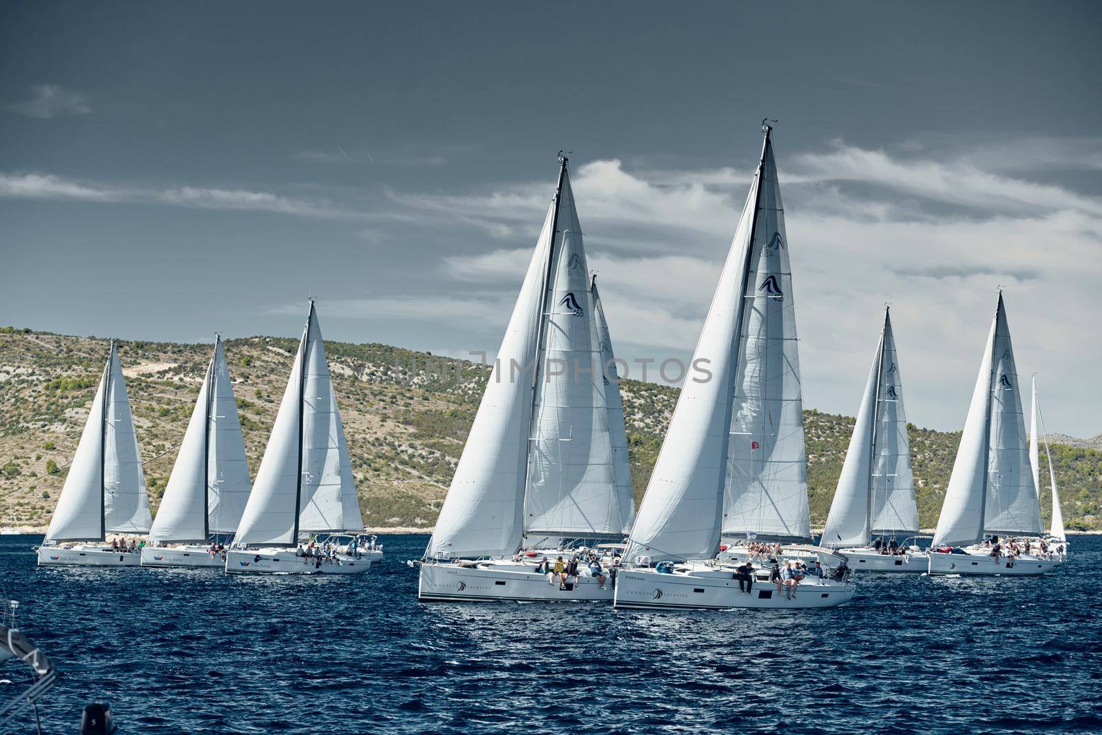 Croatia, Adriatic Sea, 18 September 2019: Sailboats compete in a sail regatta, sailboat race, reflection of sails on water, island is on background, clear weather