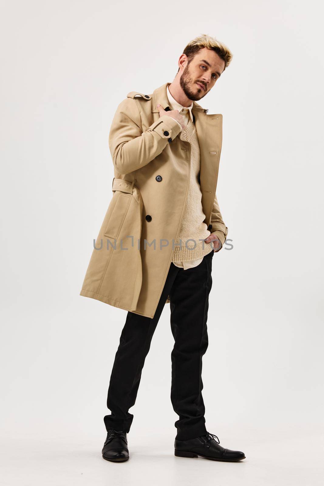 man in beige coat autumn style studio full growth side view. High quality photo
