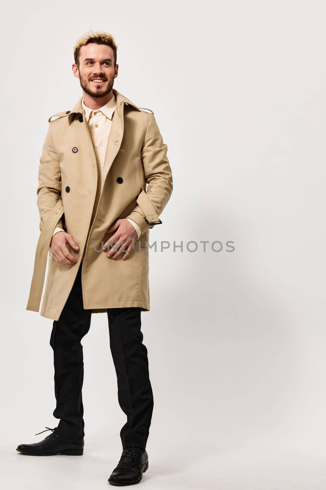 stylish guy in a beige coat holds his hands in his pocket and a blonde in a boot Copy Space by SHOTPRIME