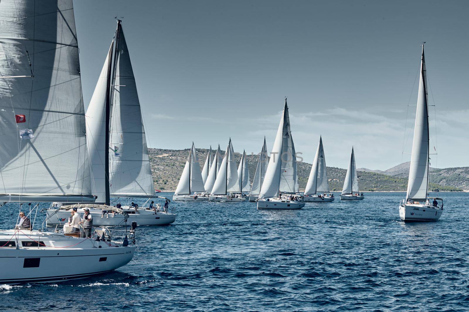 Croatia, Adriatic Sea, 18 September 2019: Sailboats compete in a sail regatta, sailboat race, reflection of sails on water, island is on background, clear weather