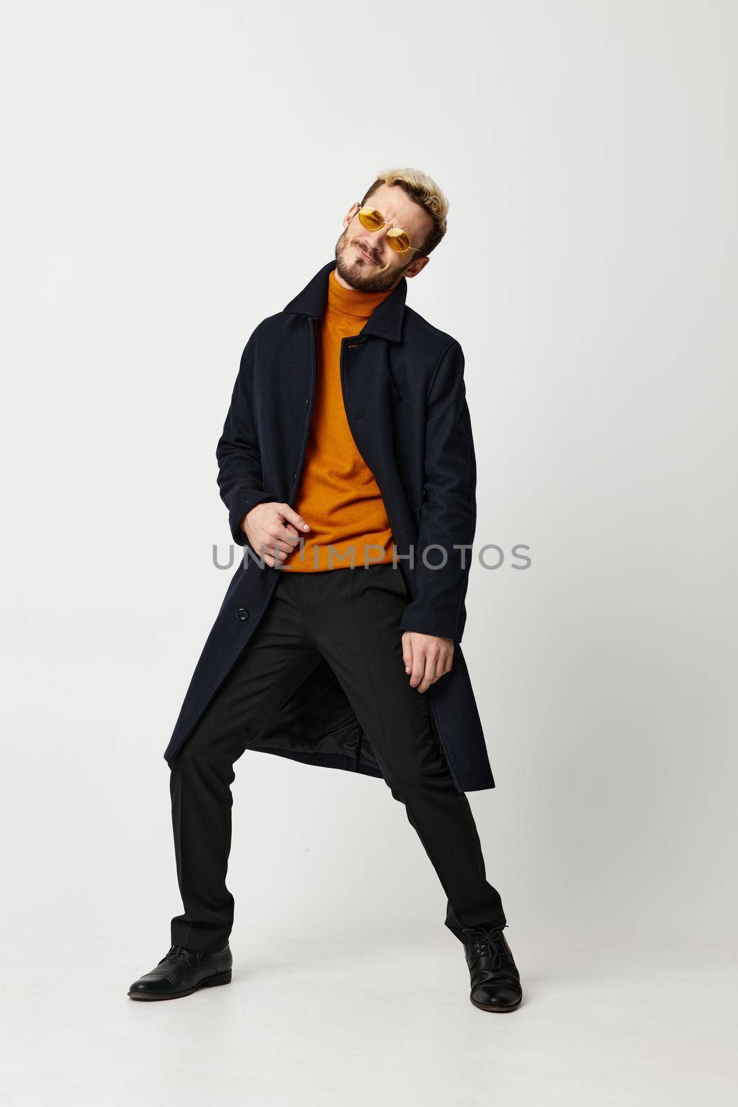 man in a dark coat orange sweater pants model emotions Copy Space. High quality photo