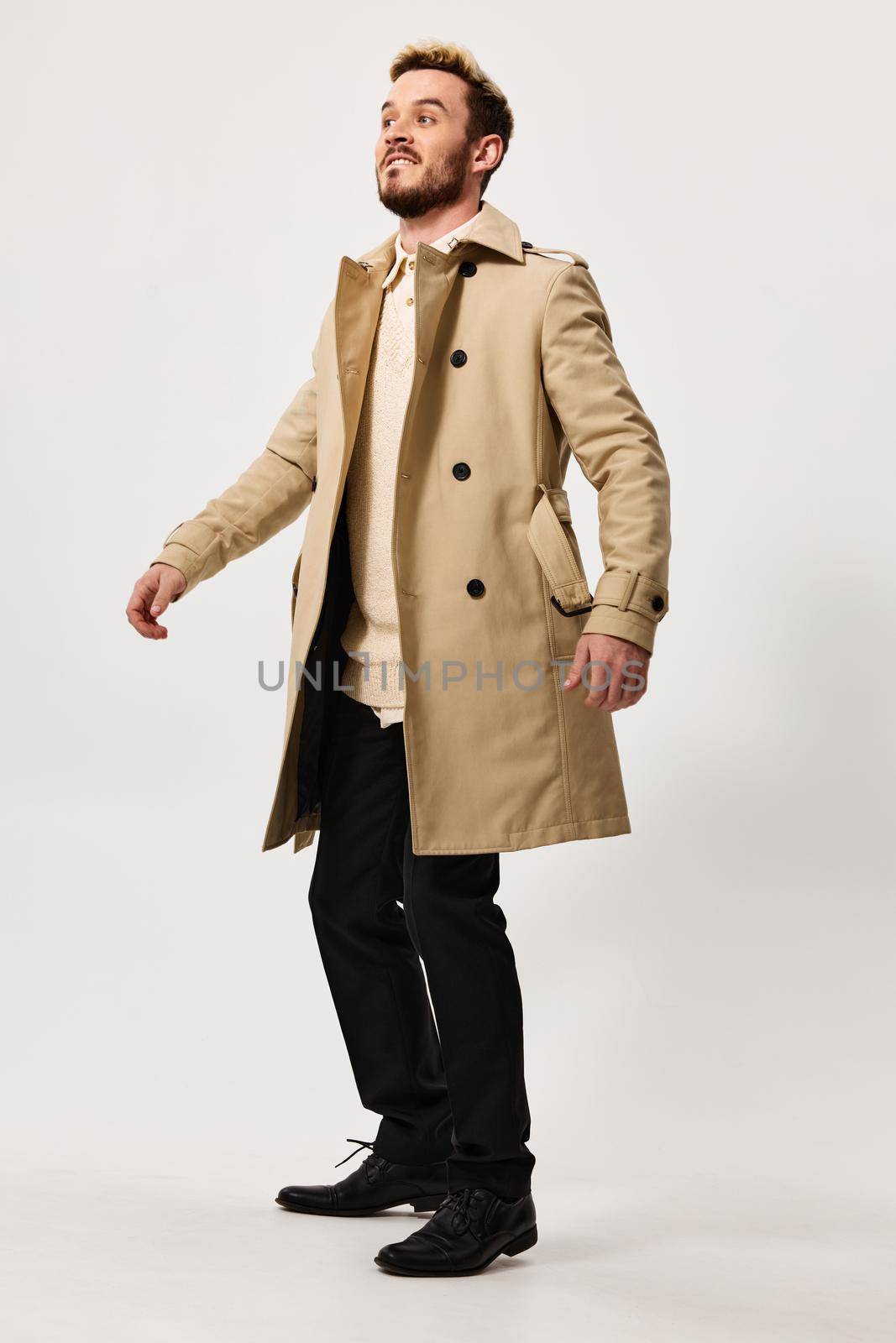 a man in a beige coat and trousers on a Light background boots Copy Space. High quality photo