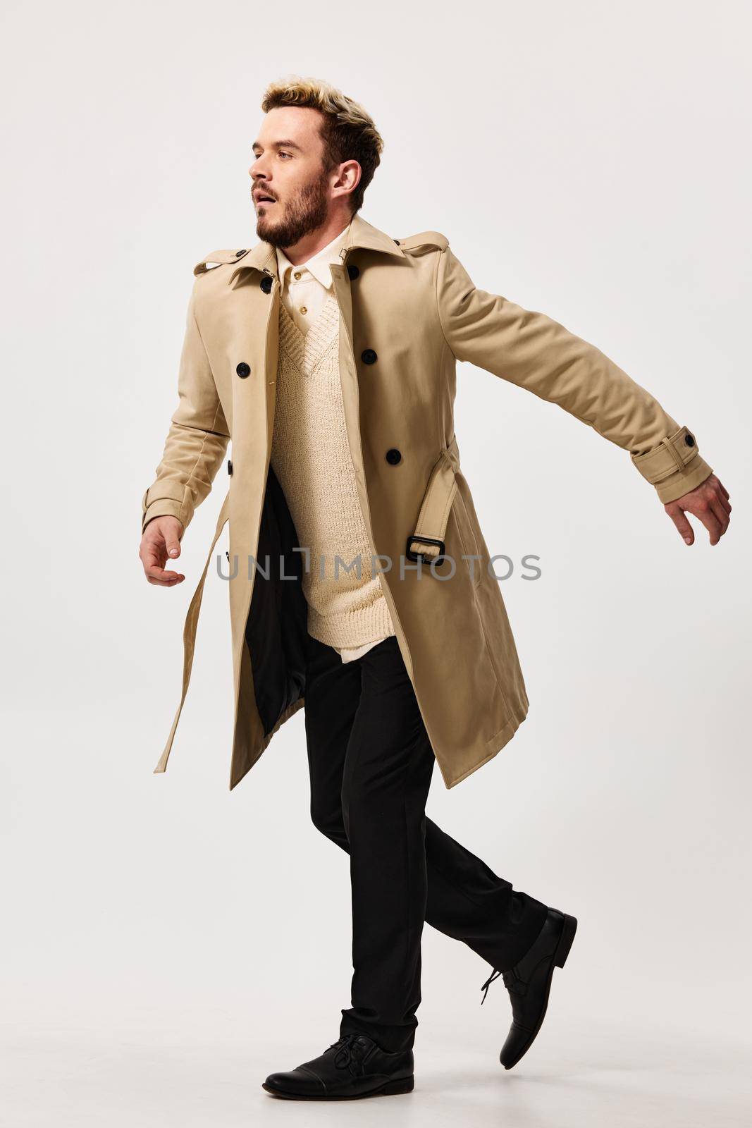 energetic man in a coat runs to the side on a light background and stylish clothes fashion by SHOTPRIME