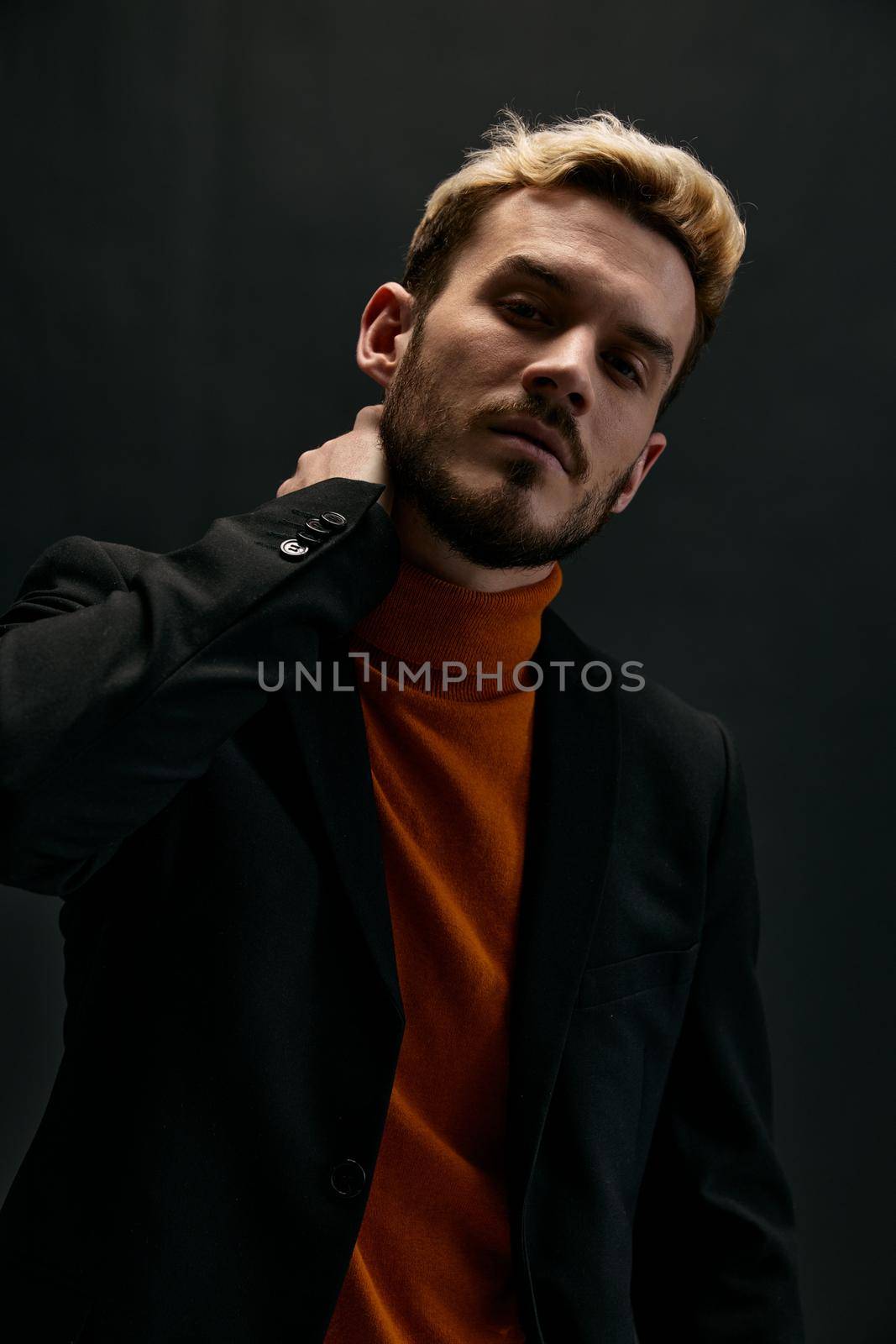 blond man in fashionable clothes on dark background and portrait close-up . High quality photo