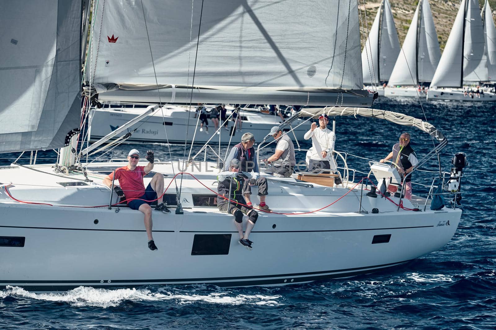 Croatia, Mediterranean Sea, 18 September 2019: The team of sailboat turns off the boat, sailboats compete in a sail regatta, The team works, pulls to a rope, the captain stands behind a steering wheel