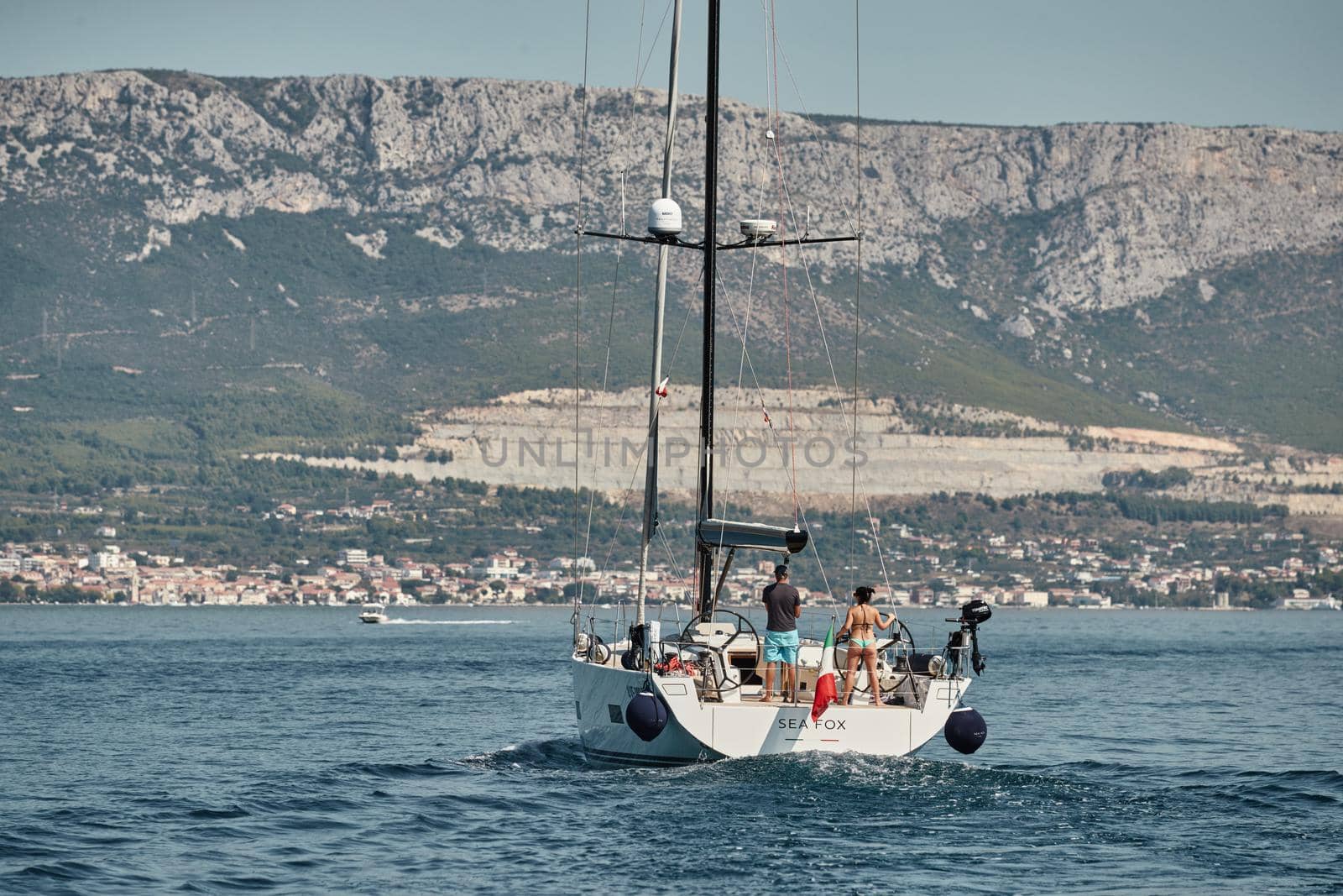 Croatia, Adriatic Sea, 15 September 2019: People have a good time on the sailboat, bright colors, island with windmills are on background by vladimirdrozdin