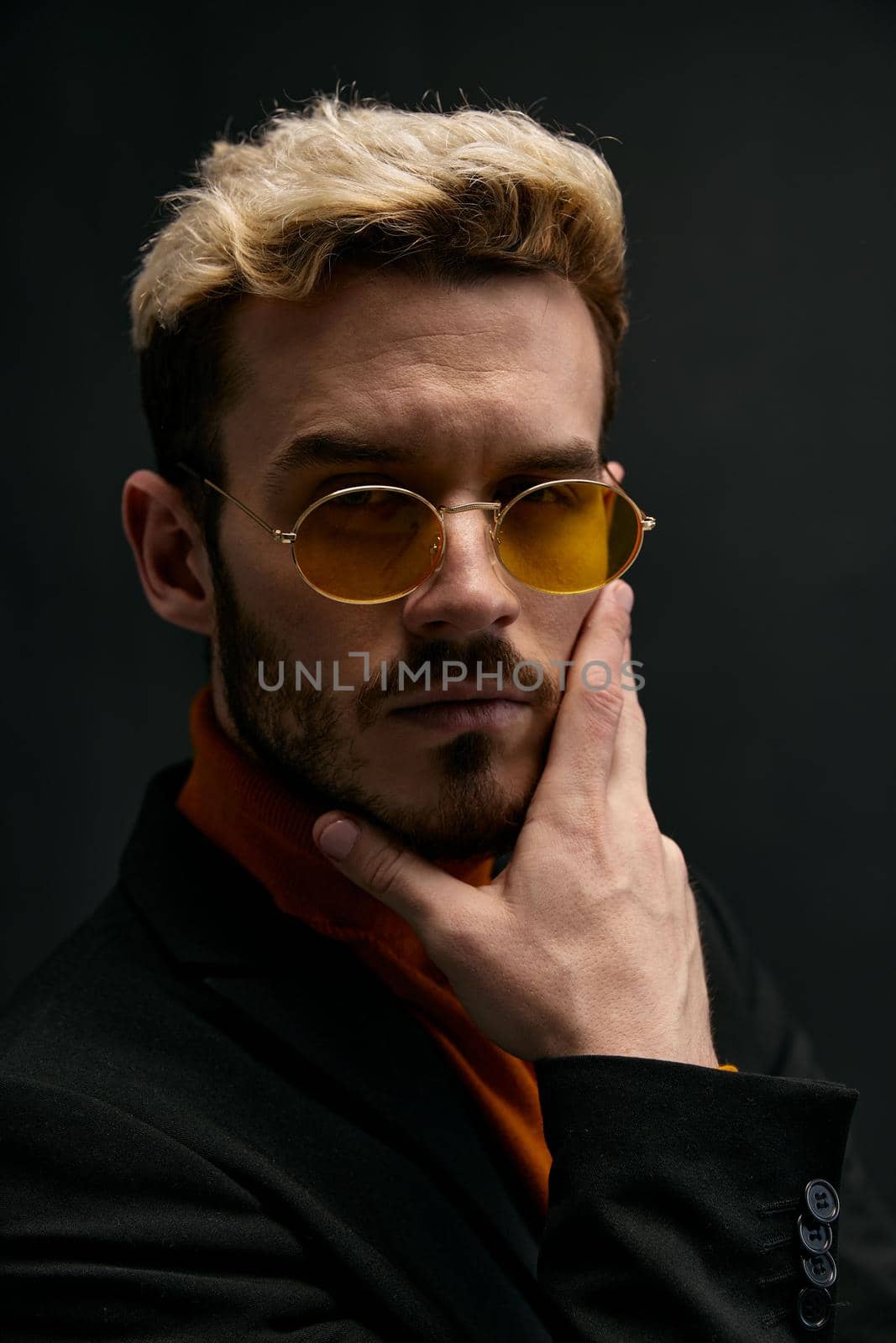 portrait of an attractive blond man gesturing with his hands on a dark background . High quality photo