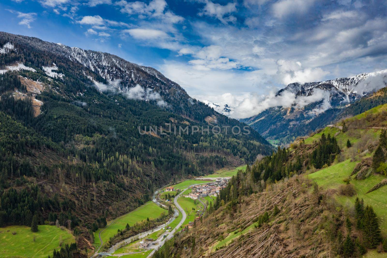 Aerial view of valley with green slopes of the mountains of Italy, Trentino, The trees tumbled down by a wind, huge clouds over a valley, green meadows, Dolomites on background