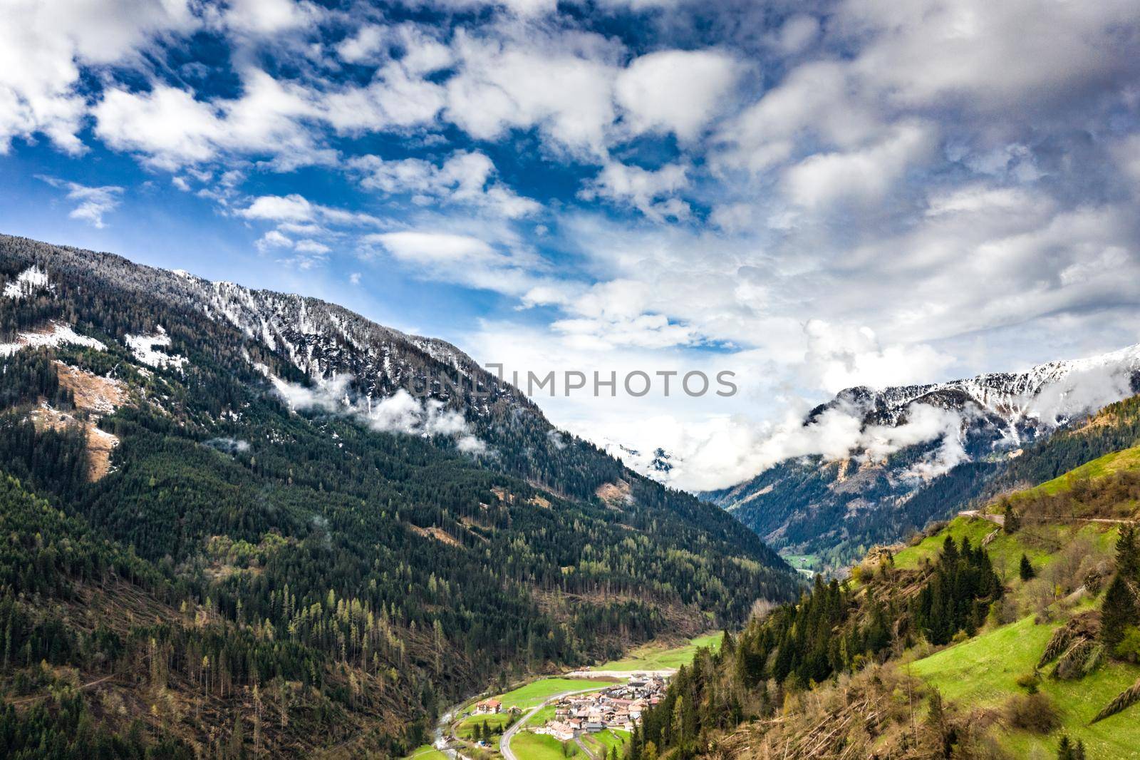 Aerial view of valley with green slopes of the mountains of Italy, Trentino, The trees tumbled down by a wind, huge clouds over a valley, green meadows, Dolomites on background