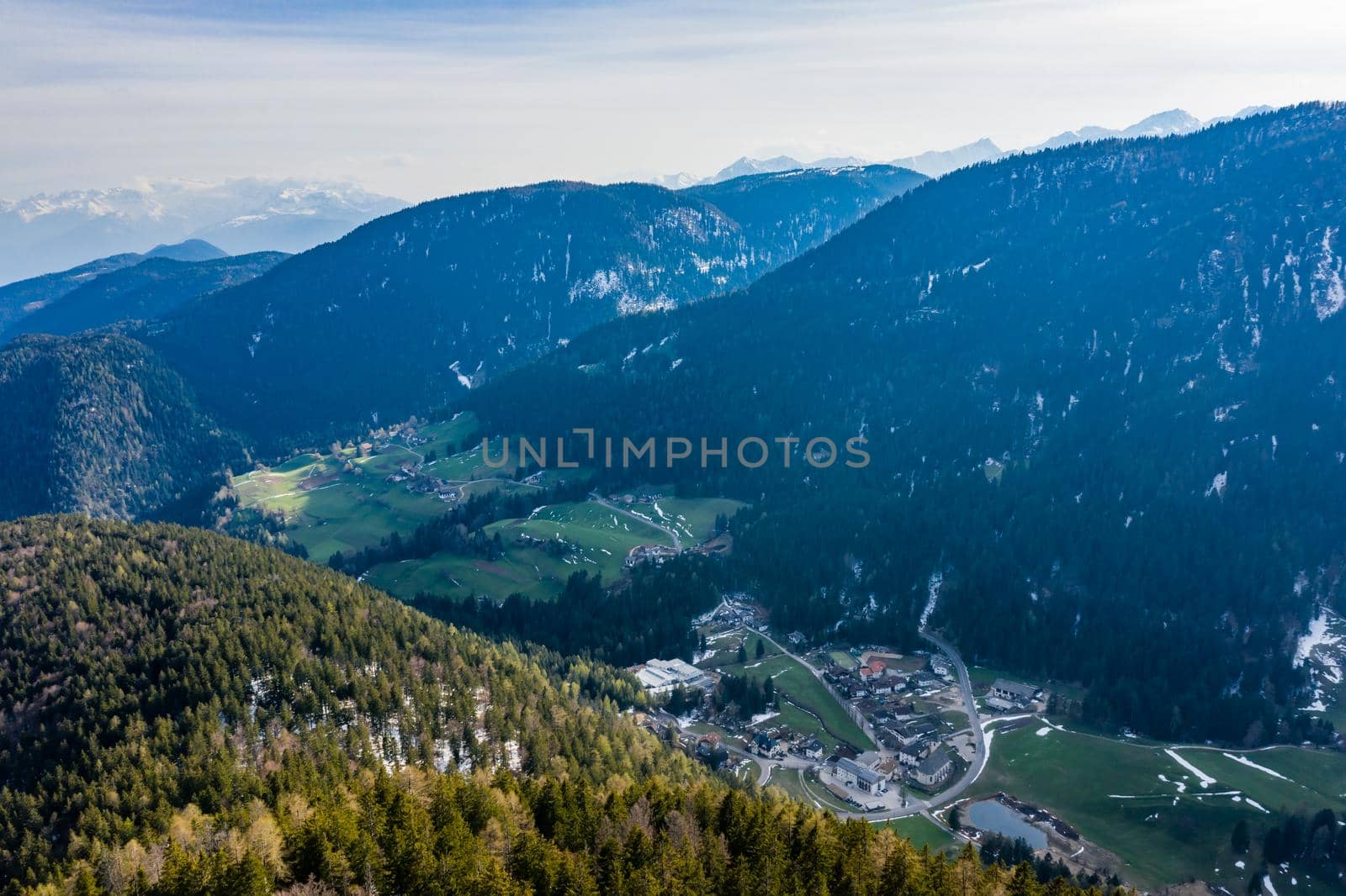 Aerial view of huge valley of the mountains of Italy, Trentino, green meadows, Slopes with green spruce trees, Dolomites on background, The town in the bottom of a valley by vladimirdrozdin