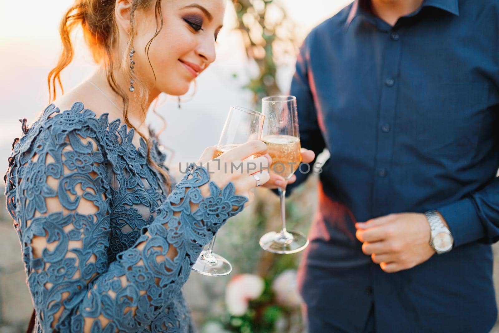 Bride and groom drink champagne from glasses near the wedding arch during the wedding ceremony . High quality photo