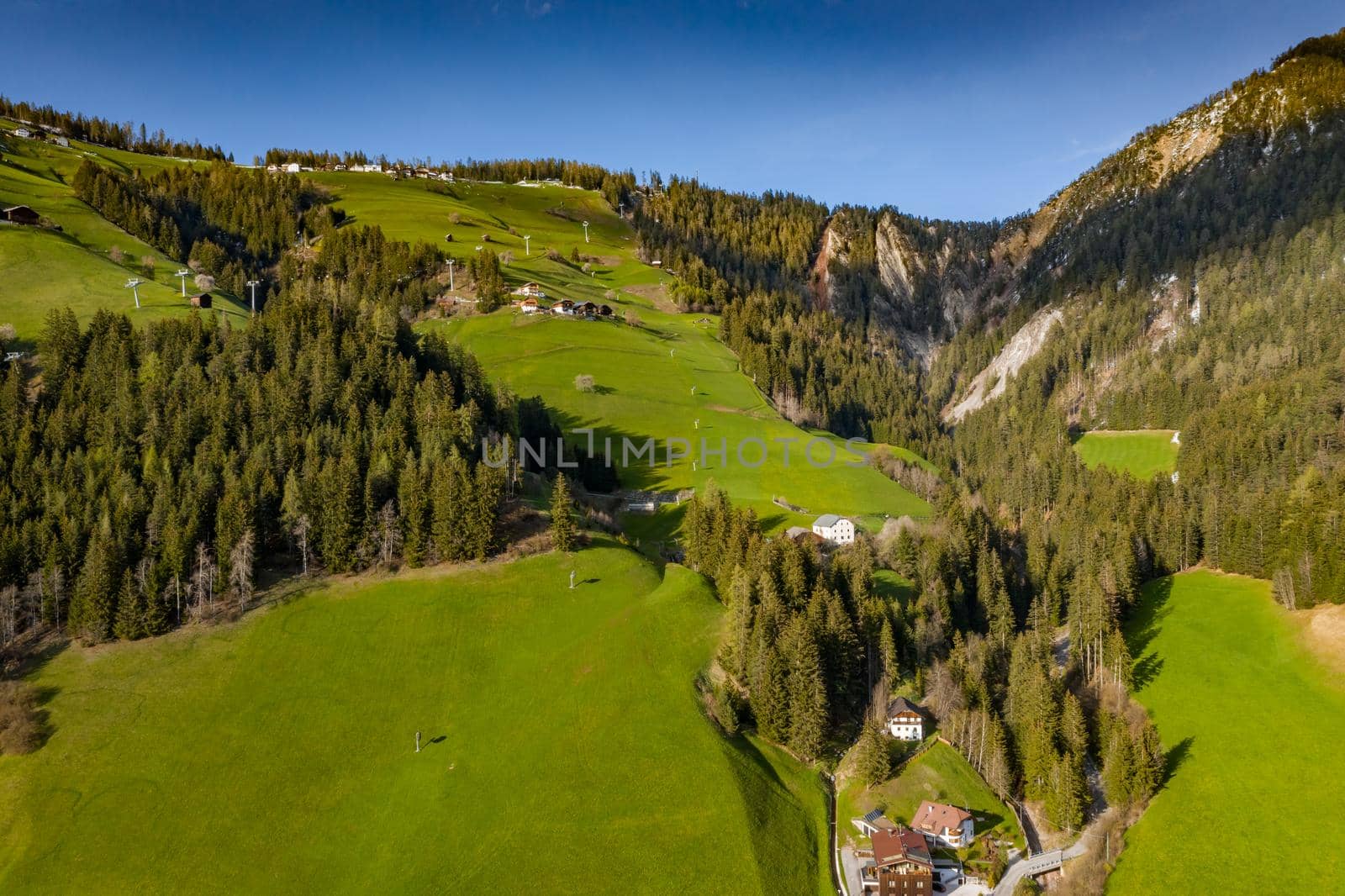 Aerial view of improbable green meadows of Italian Alps, green slopes of the mountains, Bolzano, huge clouds over a valley, roof tops of houses, Dolomites on background, sunshines through clouds by vladimirdrozdin