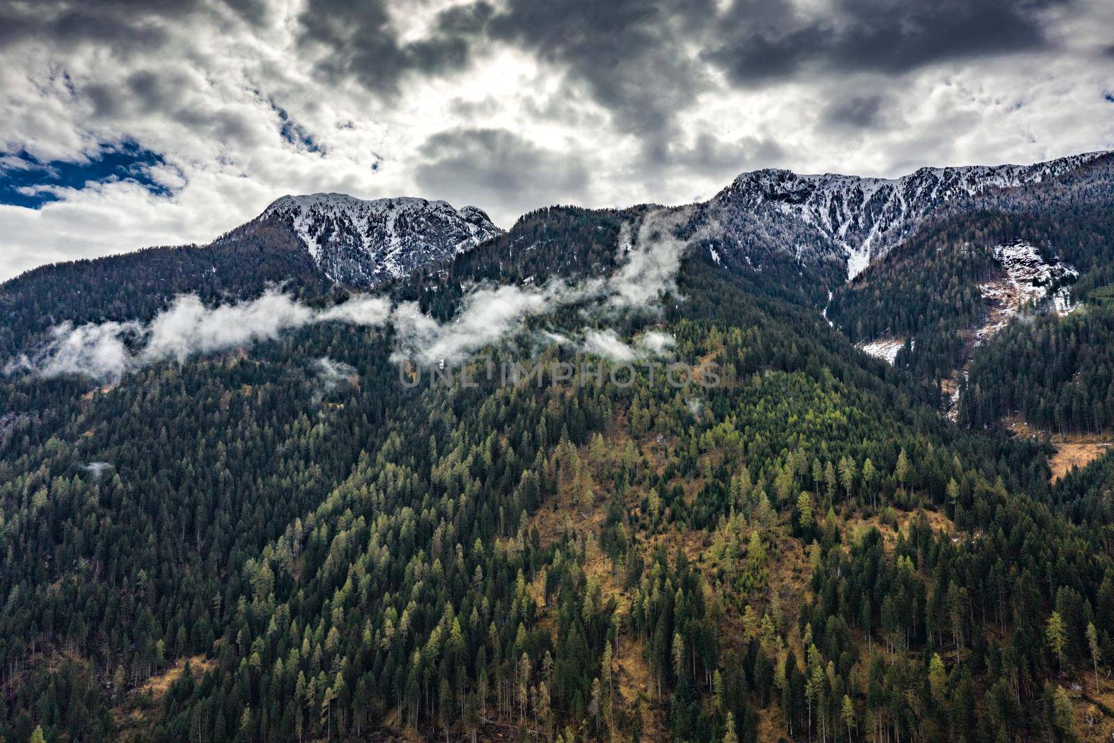 Aerial view of valley with green slopes of the mountains of Italy, Trentino, The trees tumbled down by a wind, huge clouds over a valley, green meadows, Dolomites on background