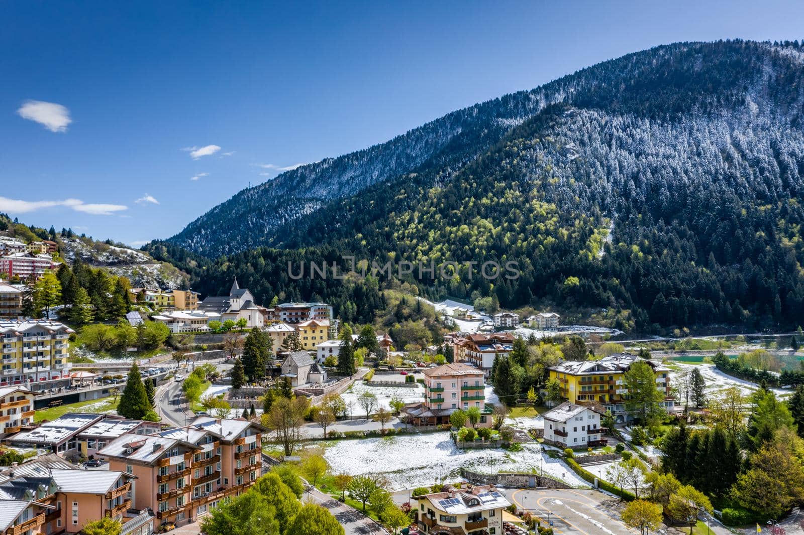 The Improbable aerial landscape of village Molveno, Italy, snow covered mountains Dolomites on background, roof top of chalet