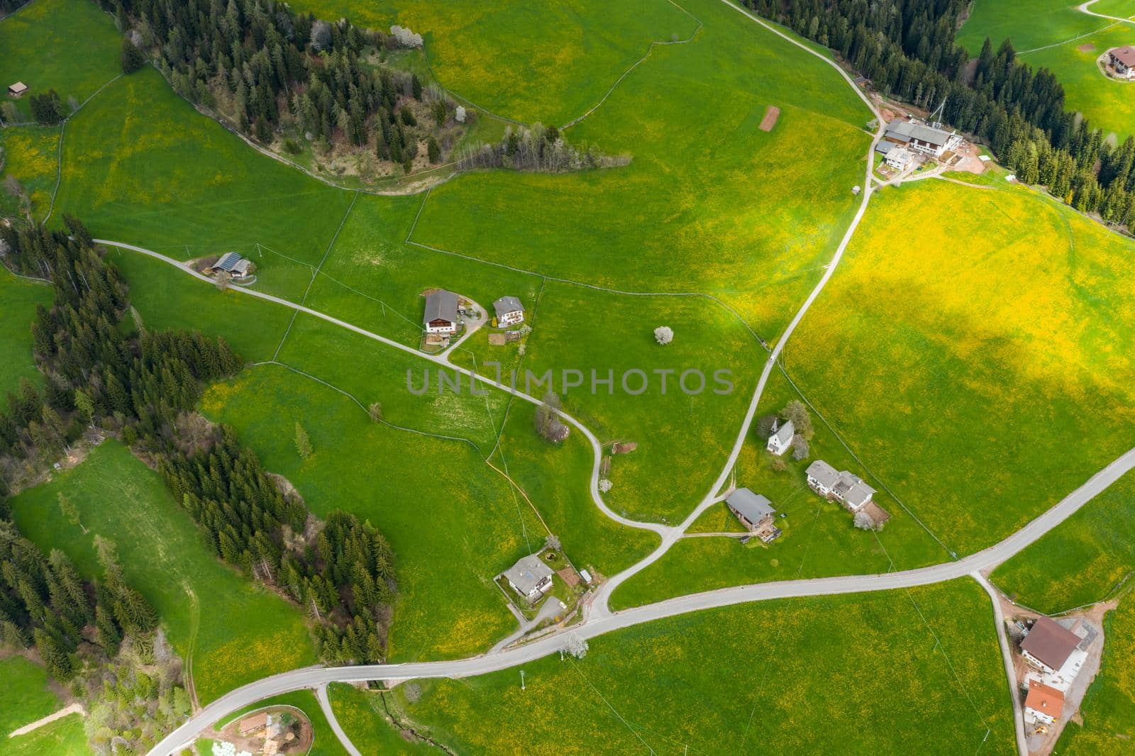 Aerial view of improbable green meadows of Italian Alps, green slopes of the mountains, Bolzano, huge clouds over a valley, roof tops of houses, Dolomites on background, sunshines through clouds by vladimirdrozdin