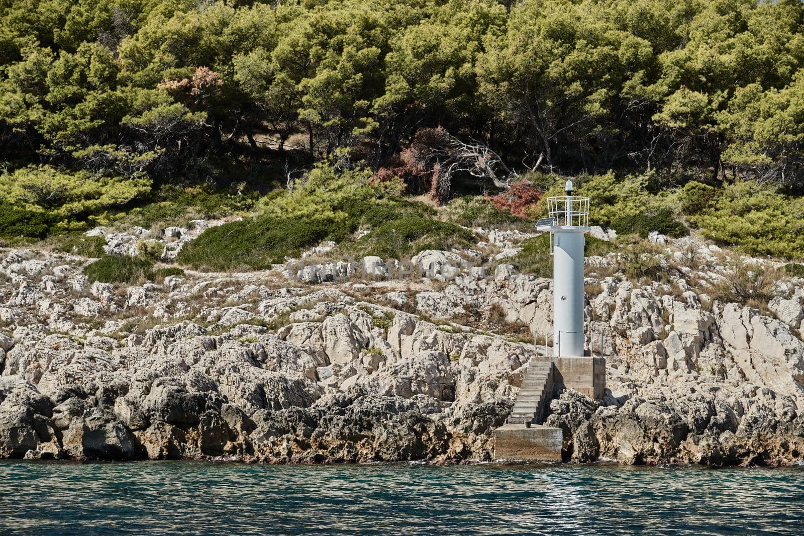 Small lighthouse on the island, Stone coast, sunny weather by vladimirdrozdin