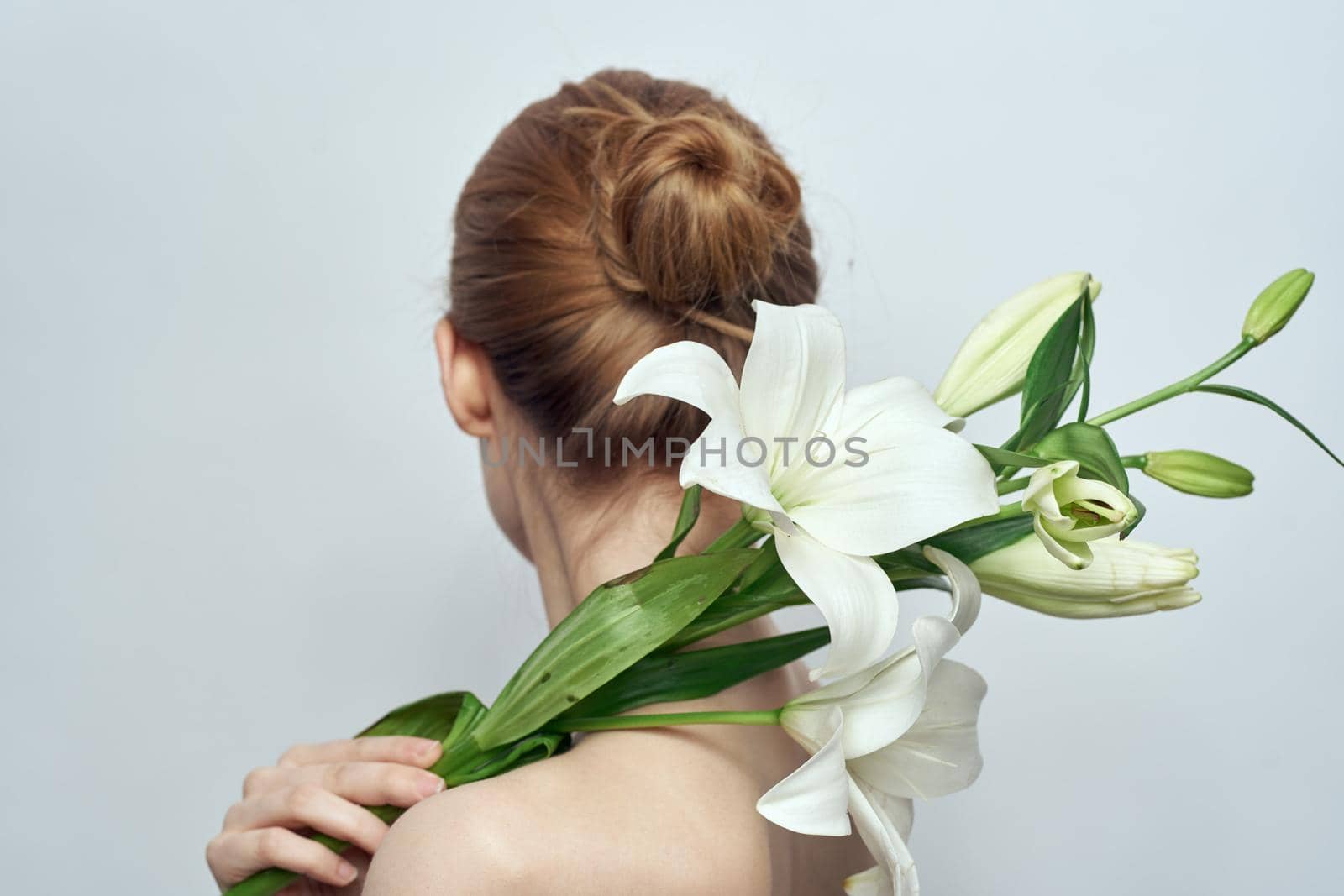 Lady with a bouquet of white flowers on a gray background portrait cropped view close-up. High quality photo