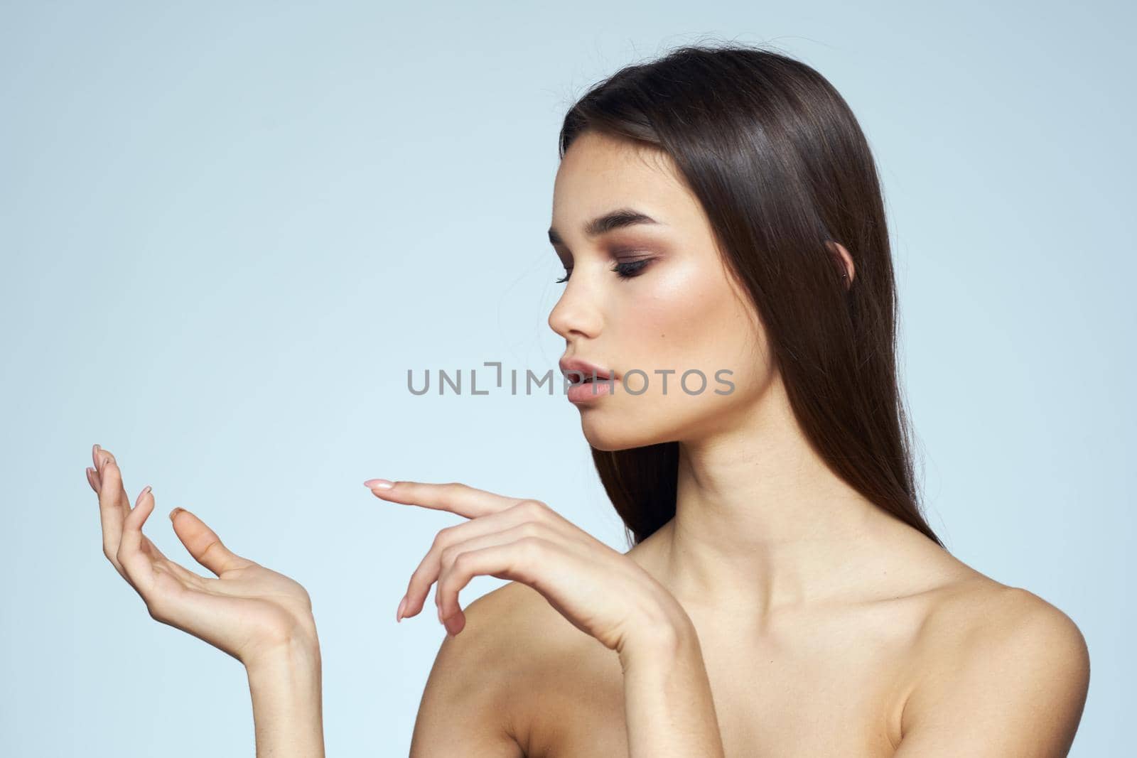 Woman with naked shoulders long hair clean skin cropped view blue background. High quality photo