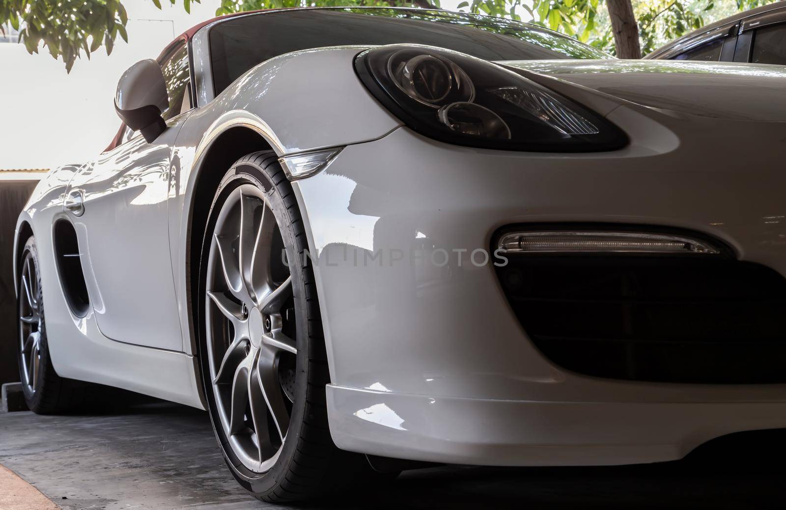 Close-up of Car Headlights and Car Wheel of White Sports Car parked in the parking lot. Selective focus.