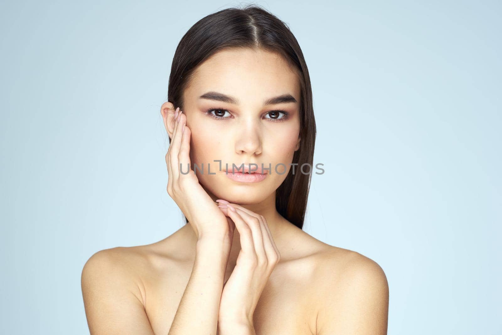 Woman with naked shoulders long hair clean skin cropped view blue background. High quality photo