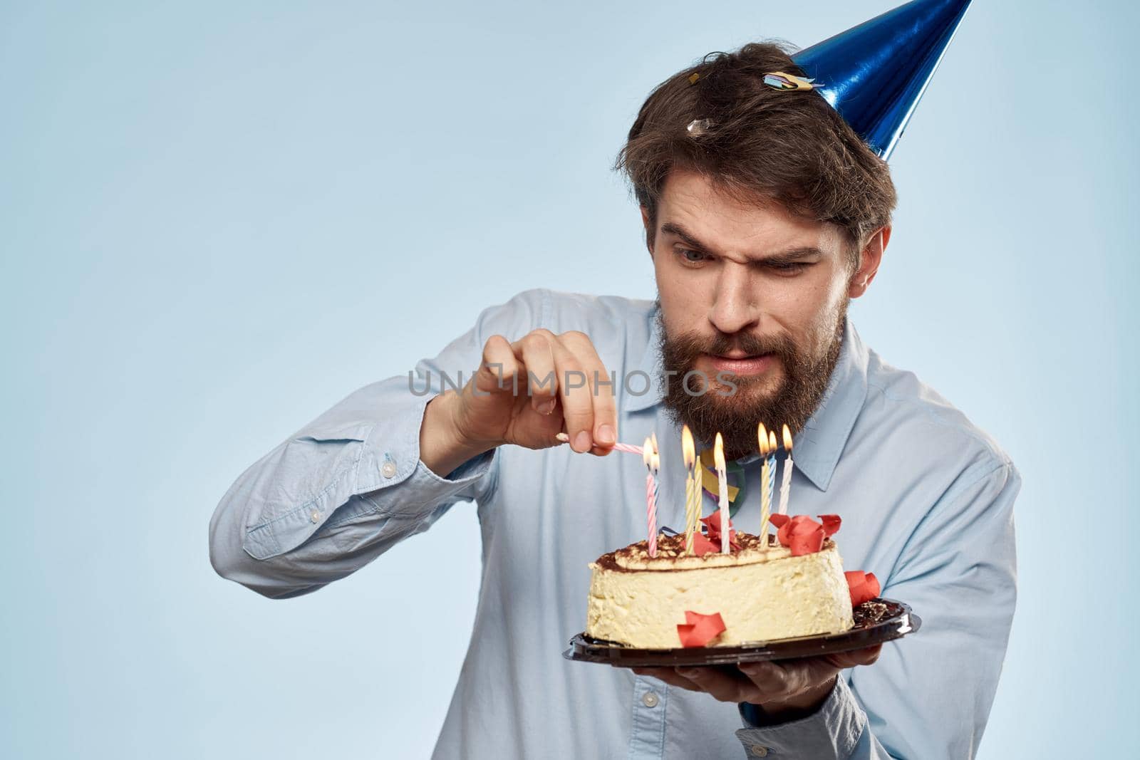 A man in a shirt with a cake in his hands and a festive cap on his head. High quality photo