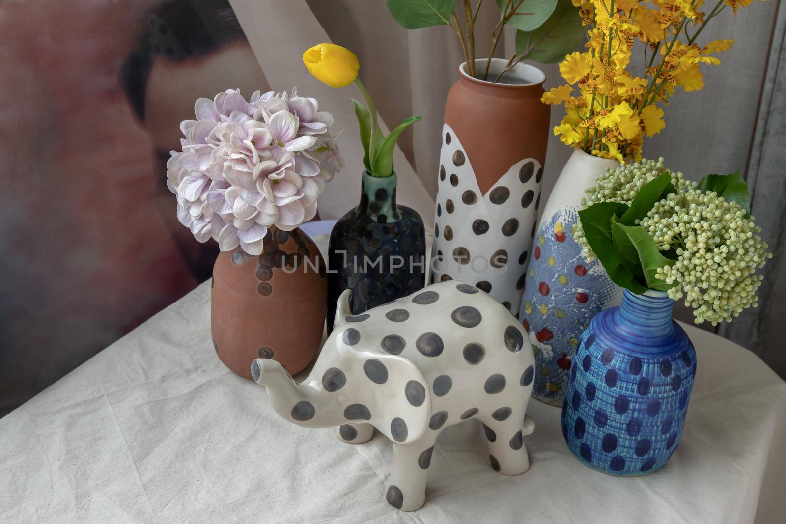Bangkok, Thailand - Feb 06, 2021: Elephant shaped ceramic and Handmade Assorted Many Different Ceramic Polka Dotted Vases on white textured table cloth. Home decor, Space for text, Selective focus.