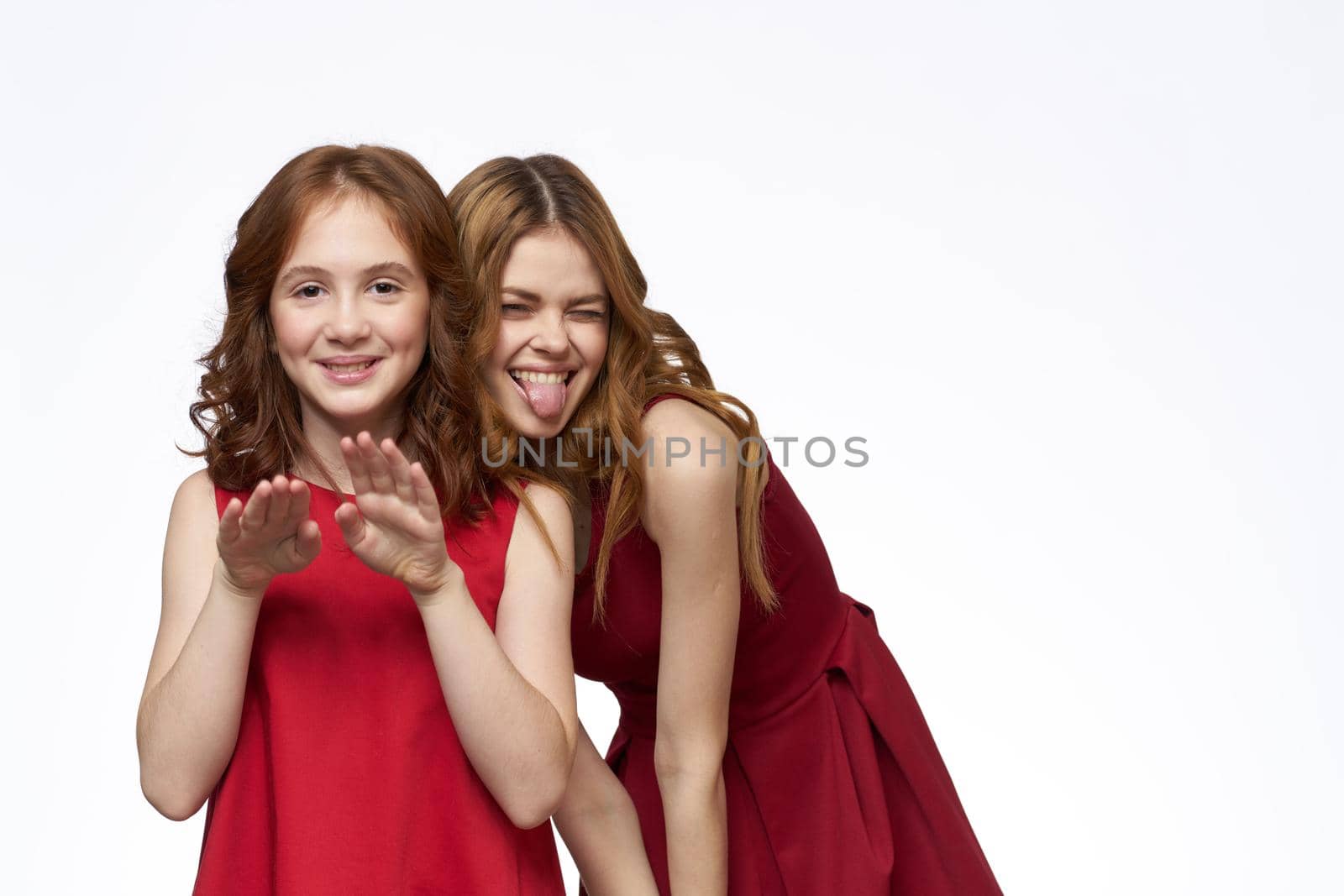 Cheerful mom and daughter next to red dresses hugs lifestyle light background smile by SHOTPRIME