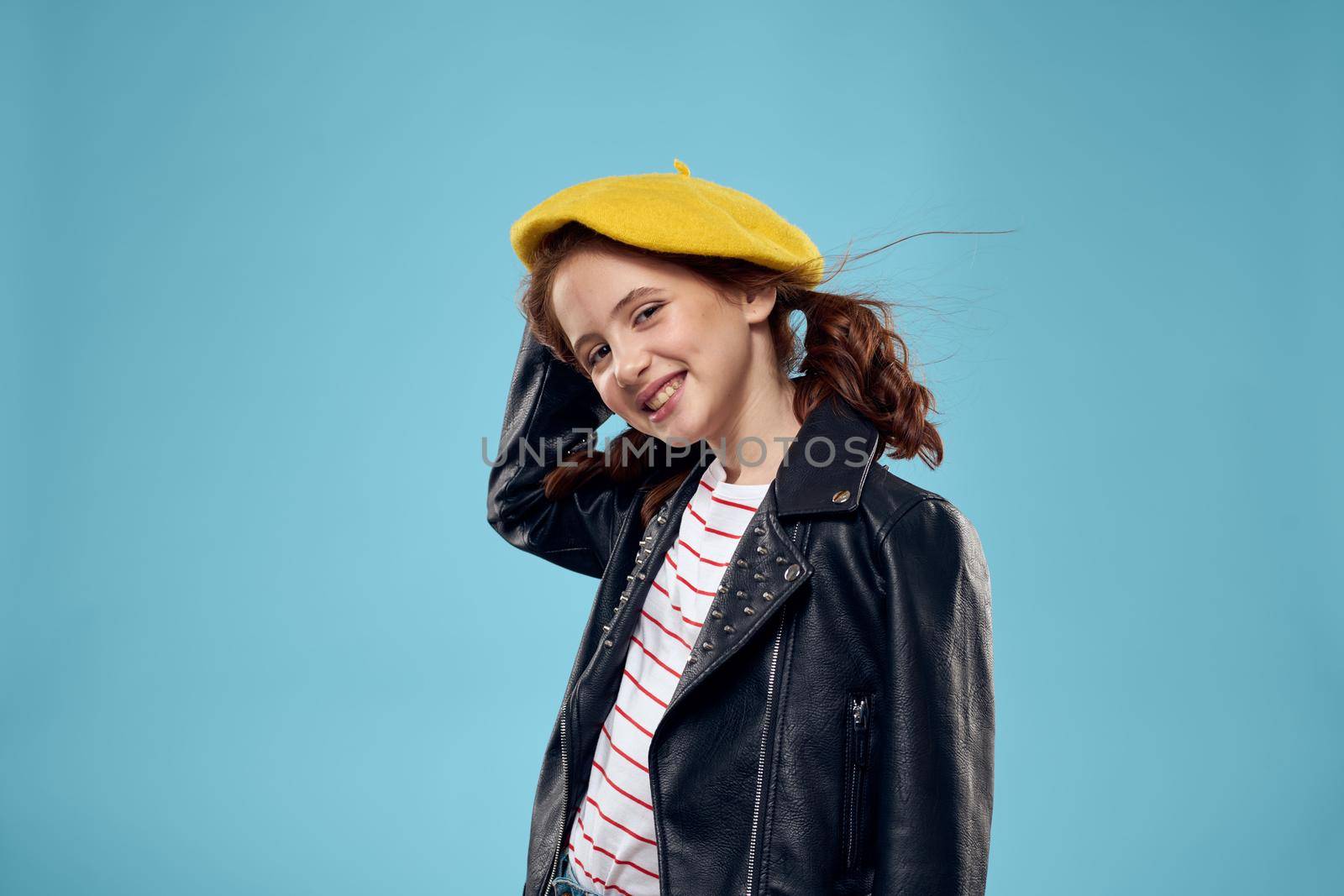 Fashionable girl in a black jacket with a yellow ticket striped T-shirt blue background by SHOTPRIME