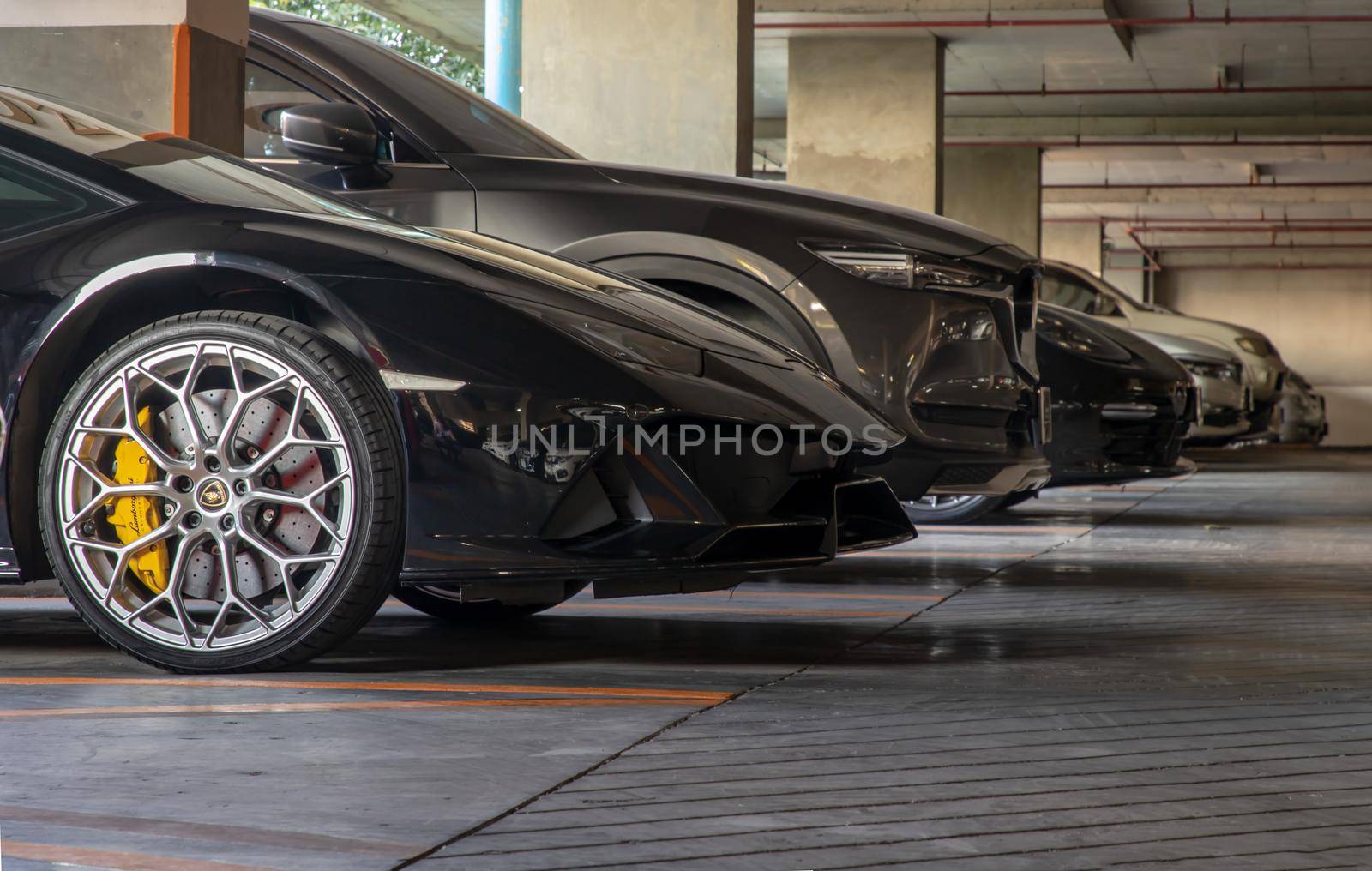 Bangkok, Thailand - 06 Jan 2021 : The side of Wheel of Black Lamborghini Sports Car parked in the parking lot. Selective focus.
