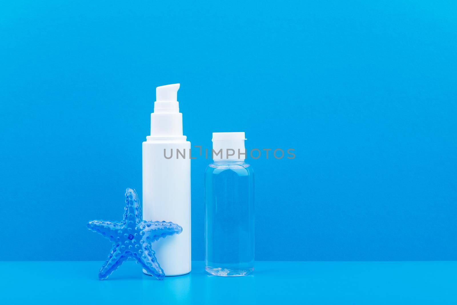 Face cream or scrub and skin lotion with star fish against blue background with copy space. Concept of natural cosmetics with sea salt or tangle extract