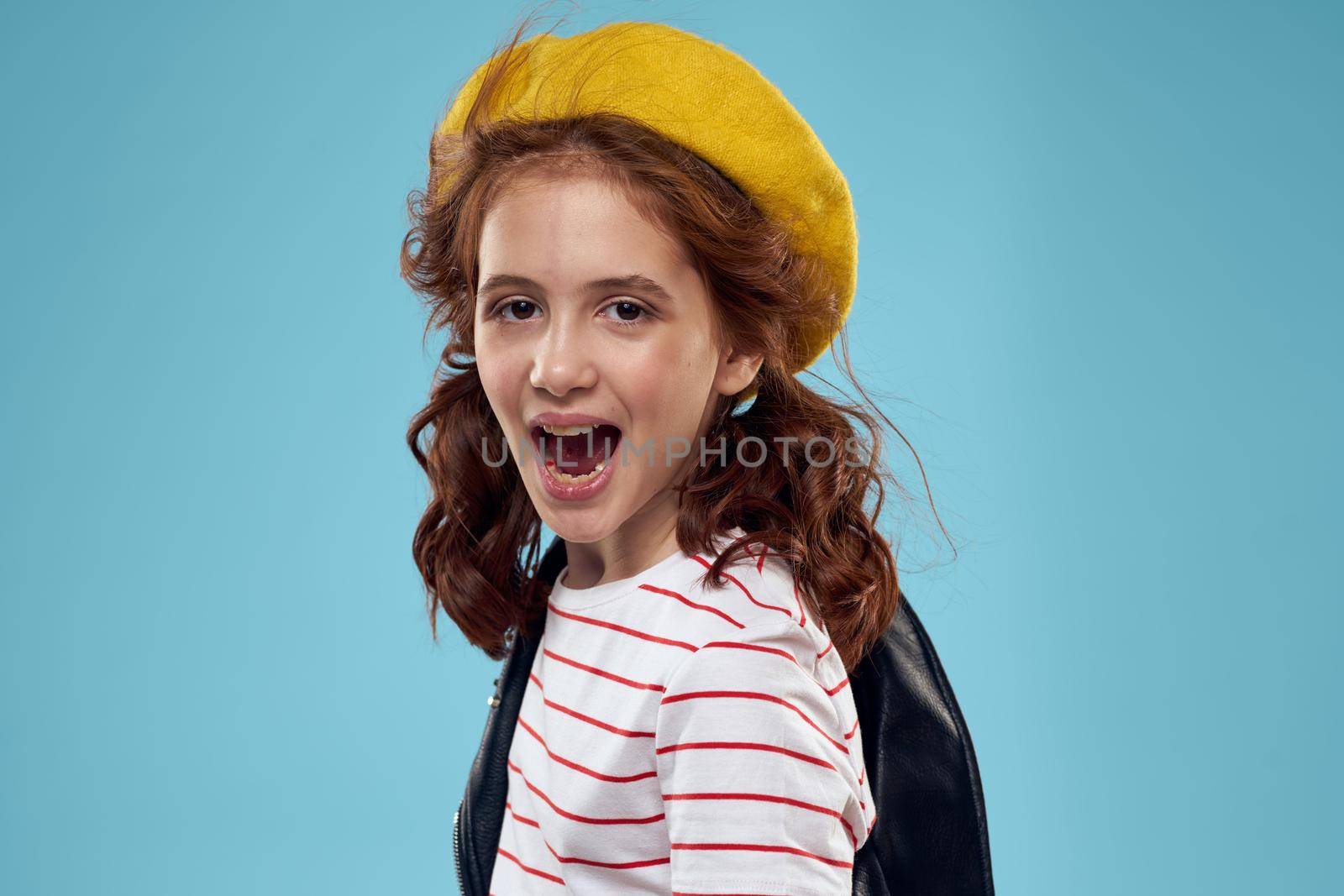 Fashionable girl in a black jacket with a yellow ticket striped T-shirt blue background. High quality photo